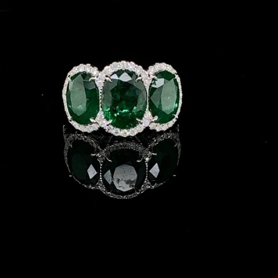 A THREE STONE EMERALD AND DIAMOND CLUSTER RING