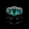 A THREE STONE EMERALD AND DIAMOND RING