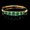 AN EMERALD AND DIAMOND HINGED BANGLE